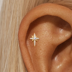 Close-up of golden octagram star ear stud with zircons worn on the cartilage