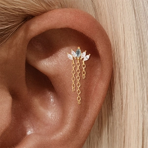 Κοντινό πλάνο χρυσού ear cuff με πέτρες marquise και λεπτές κρεμαστές φούντες