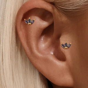 Detail van gouden kroon oorbellen met regenboog marquise stenen op helix en tragus piercing