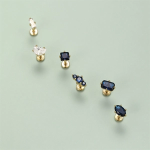 Macro detail of six S925 sterling silver gold-plated stud earrings with blue zircons