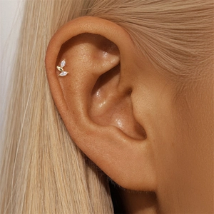 Macro detail of gold marquise zircon leaf stud earring on ear cartilage