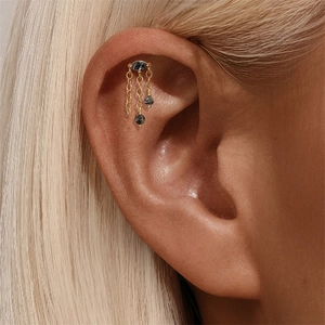 Vue macro d'un piercing cartilage 16G doré avec quartz rutilé et pampilles pendantes