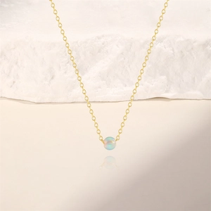 Nahaufnahme eines runden Opal-Anhängers an einer minimalistischen verstellbaren Goldkette