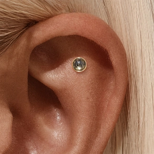 Macro shot of s925 silver ear stud with black rutilated quartz in gold setting