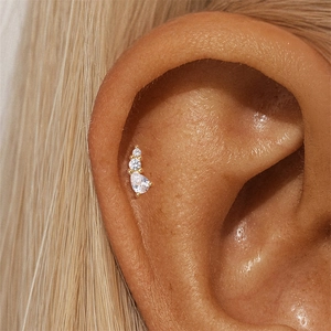 Macro shot of gold S925 silver cartilage stud featuring three-stone leaf-like zircon cluster