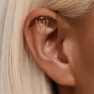 Gros plan d'un piercing hélix doré avec gemmes marquises noires et chaînes à franges