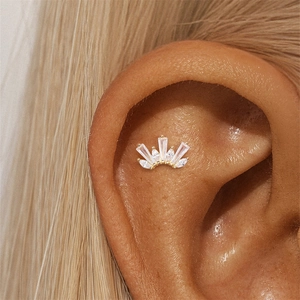 Macro view of a 16G gold crown zircon leaf stud earring on the ear cartilage