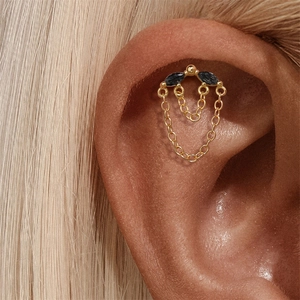 Détail d'un clou d'oreille en argent 925 doré avec pierres noires et doubles glands