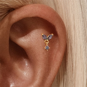 Close-up van gouden helix piercing met iriserende marquise steentjes en ronde hanger