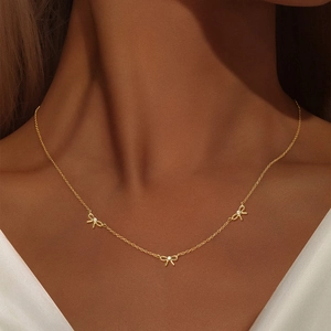 Gros plan d'un collier doré avec nœuds et zircons étincelants porté par un modèle