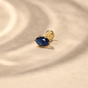 Macro shot of S925 sterling silver flat back earring with blue oval zirconia in gold