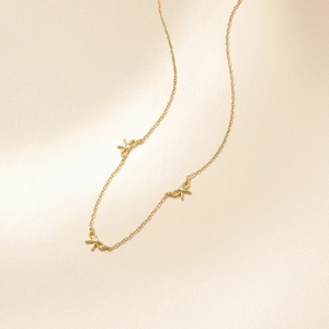 Vue macro du collier nœud doré orné de petites pierres scintillantes sur une chaîne fine
