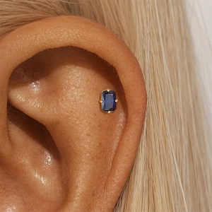 Macro side view of a rectangle blue zircon stud earring with a gold four-prong setting