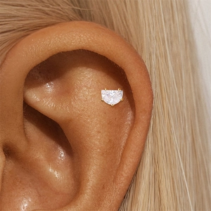 Close-up of golden crescent moon cartilage stud earring with cubic zirconia on ear