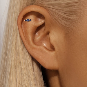 Close-up of three blue zircon stones set in gold S925 silver studs on a woman ear