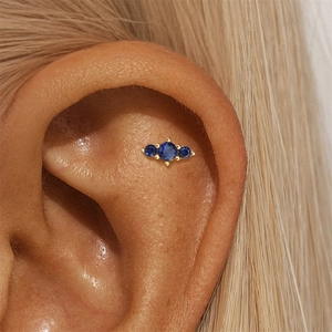 Macro shot of gold S925 sterling silver studs with three sparkling blue round zircons