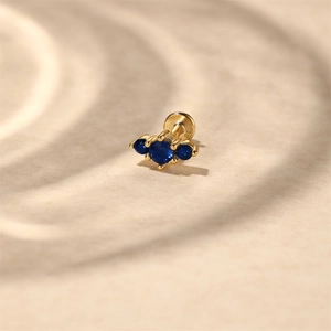 Close-up of S925 hallmark on gold-plated stud with three dark blue cubic zirconia stones