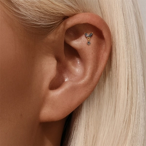 Macro view of gold S925 sterling silver ear piercing with marquise cut gemstones