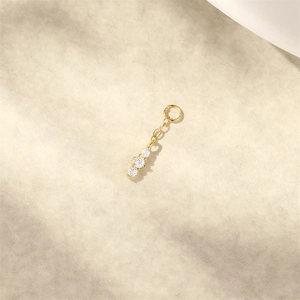 Dettaglio di tre ciondoli tondi in zircone dorato con anelli per orecchini eleganti