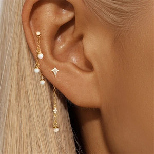 Detail of s925 silver gold-plated cartilage chain earring with white opal beads and star stud