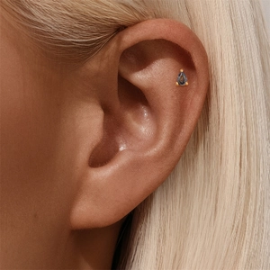 Detail van helix piercing met peervormige paarse edelsteen in goudkleurige s925 setting