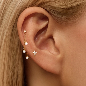 Macro shot of gold star earring with opal beads drop chain on model's ear