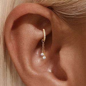 Dettaglio dell'orecchino ear cuff dorato con doppia nappa a catena e pietre lucide