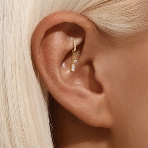 Dettaglio ear cuff dorato con pendenti in zirconia cubica rotondi e rettangolari