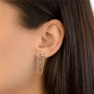 Detail of three-tier gold chain tassel earrings with sparkling diamond studs on a model