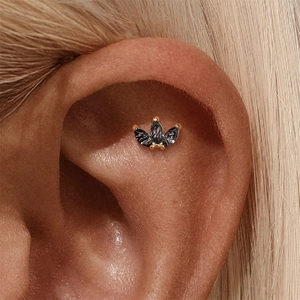 Close-up of a gold piercing stud featuring three marquise-cut black crystals in a crown shape
