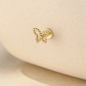 Macro shot of gold S925 silver butterfly stud earring with delicate bead texture