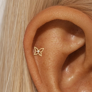 Close-up of a gold butterfly cartilage stud earring with a sparkling center zircon