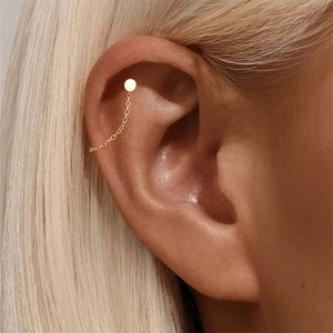 Detailed close-up of a minimalist gold-plated chain earring with stud and cartilage cuff