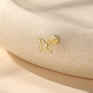 Detailed macro of a gold bow-shaped S925 sterling silver cartilage earring stud
