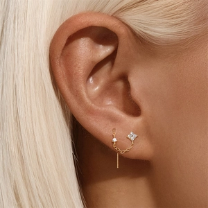 Macro shot of s925 silver golden flower earrings with dangling chain and zircon studs