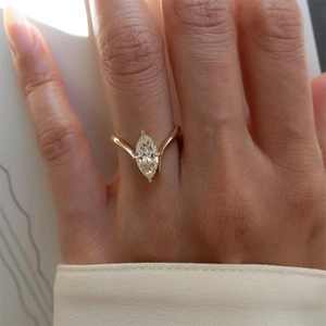Close-up of a marquise-cut solitaire diamond ring on a minimalist chevron gold band