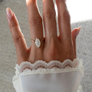 Detailed view of marquise cut zircon ring with gold band on a hand with lace sleeve