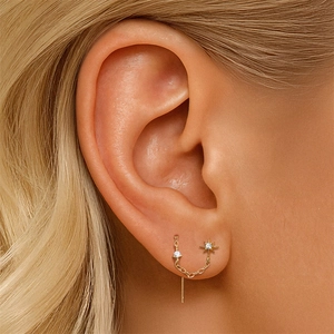 Detail of s925 silver gold star and stud earring chain dangling on a woman's ear