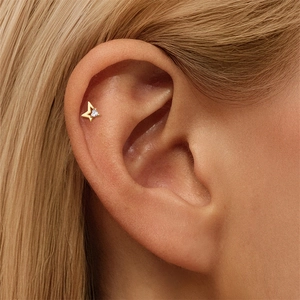 Detailed view of a gold star stud earring with a heart-shaped crystal on the ear cartilage