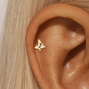 Macro detail of a 16G gold star cartilage stud featuring a heart-shaped zircon stone