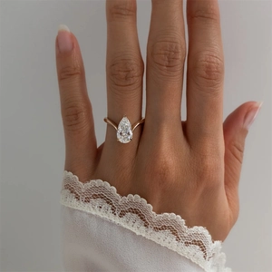 Close-up of a pear-shaped zircon ring with a V-shaped band on a model's hand