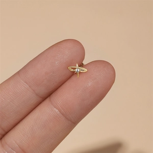 Macro detail of tiny s925 silver gold star earring with zircon held by fingers