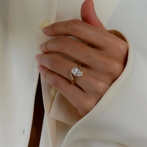 Close-up of an oval-cut zircon ring in a gold-plated setting worn on a finger