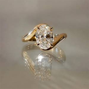 Macro shot of oval cut diamond ring with gold bypass band and stunning reflection