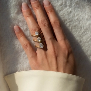 Detailed view of a triple-layer gold ring with pear-cut cubic zirconia stones on silk