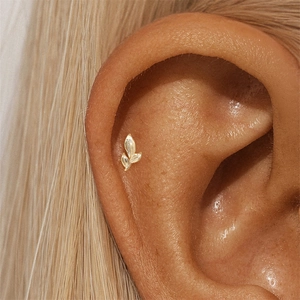Detailed view of s925 silver golden leaf cartilage stud earring on model's ear