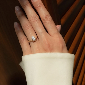 Macro detail of pear-shaped cubic zirconia ring with gold V-shaped minimalist band