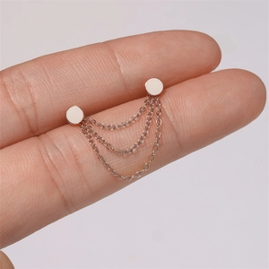 Macro detail of minimalist rose gold S925 silver chain earrings held between fingers