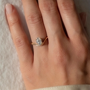 Close-up of elegant gold wave ring with a large pear-cut zircon stone on model hand
