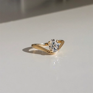 Detailed view of an oval-cut diamond set in a gold V-shaped ring with four-prong setting